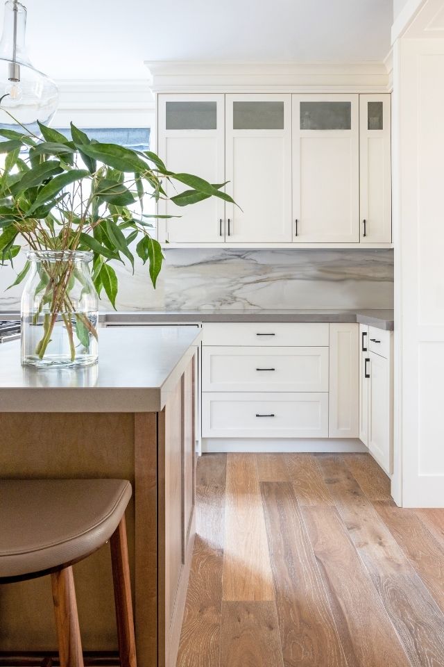 White cabinetry in kitchen with hardwood and gray countertops by Louis Duncan-He